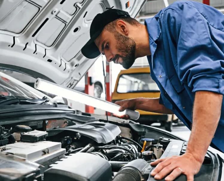 Kwik Kar technician inspecting an engine under the hood